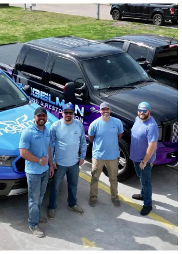 The Angelman Roofing crew standing in front of their branded work trucks